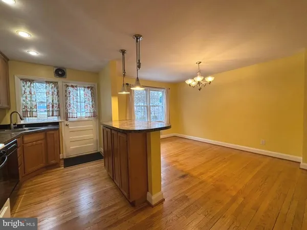 a kitchen with kitchen island granite countertop wooden floors and wide window