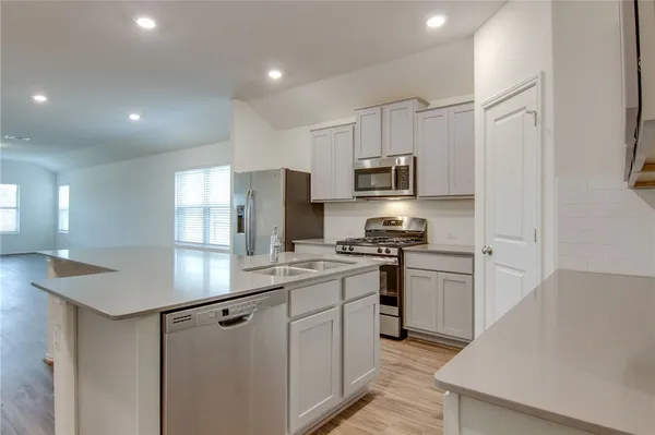 a kitchen with stainless steel appliances a stove refrigerator sink and microwave