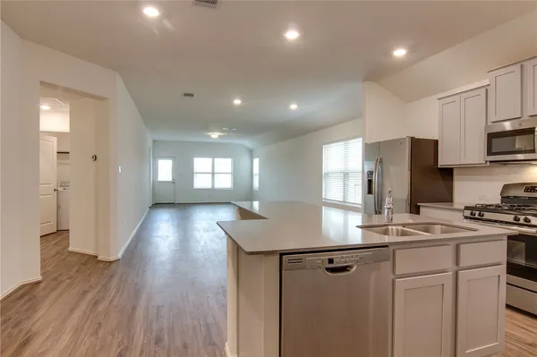 a kitchen with stainless steel appliances granite countertop a sink a stove a refrigerator cabinets and wooden floor