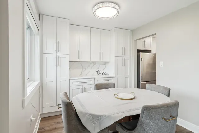 a kitchen with stainless steel appliances kitchen island a table chairs and refrigerator