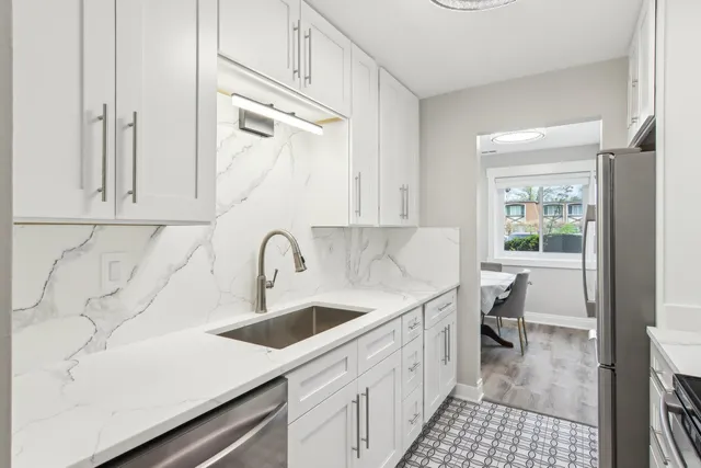 a kitchen with a sink dishwasher and white cabinets with wooden floor
