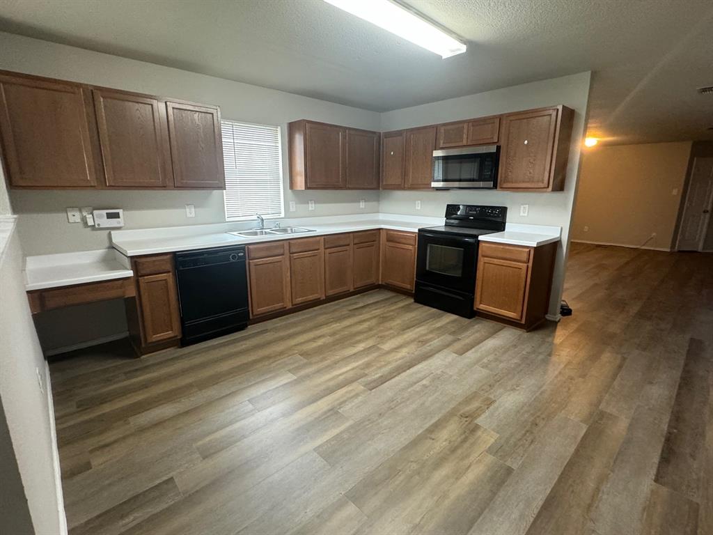 a large kitchen with stainless steel appliances granite countertop a sink dishwasher stove and wooden cabinets
