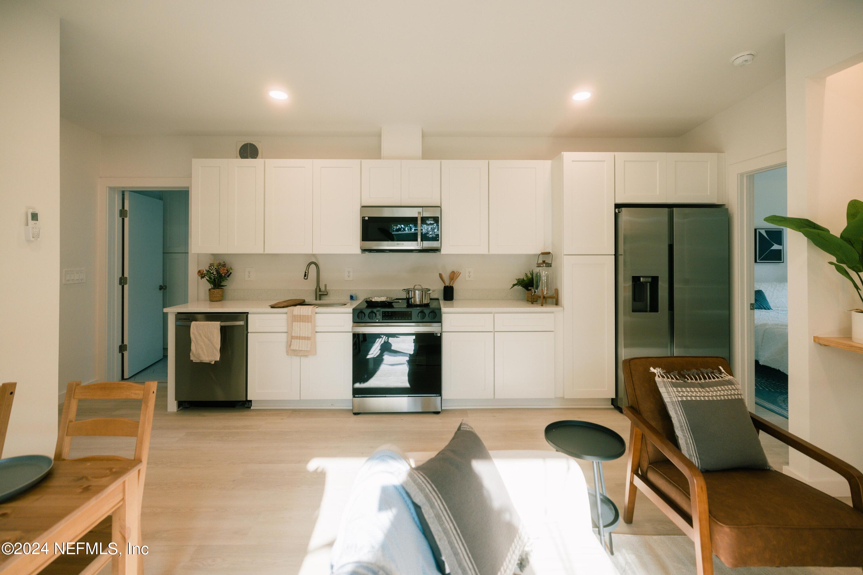 673 Julia Street St. Augustine, FL 32084 - Photo 7 of 21 a kitchen with a refrigerator a stove top oven a sink dishwasher and white cabinets with wooden floor