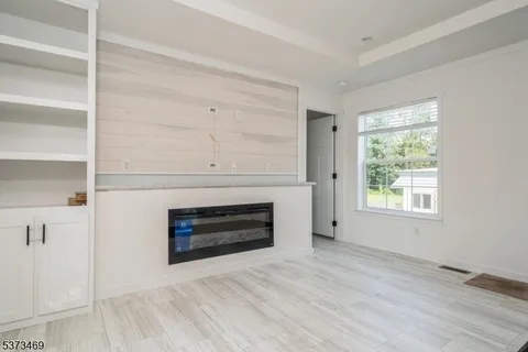 a view of an empty room with wooden floor fireplace and a window