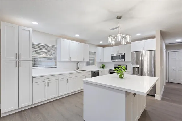 a view of a kitchen with kitchen island a sink stainless steel appliances and cabinets