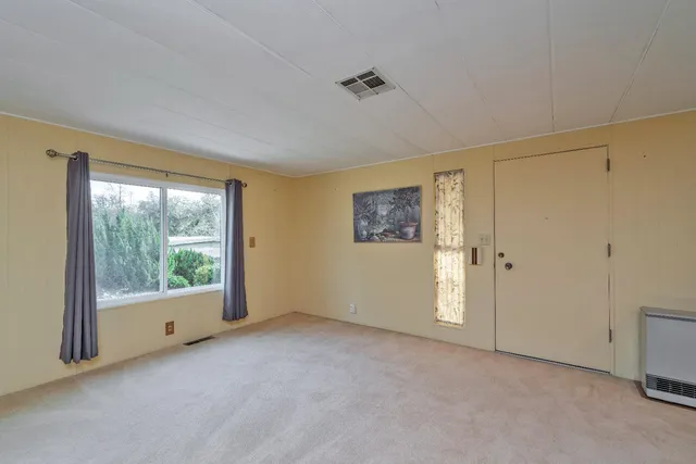 an empty room with chandelier fan and windows