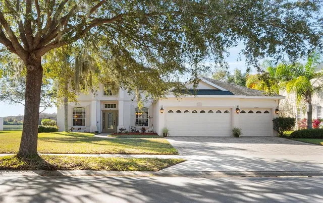 a front view of a house with a yard and large trees