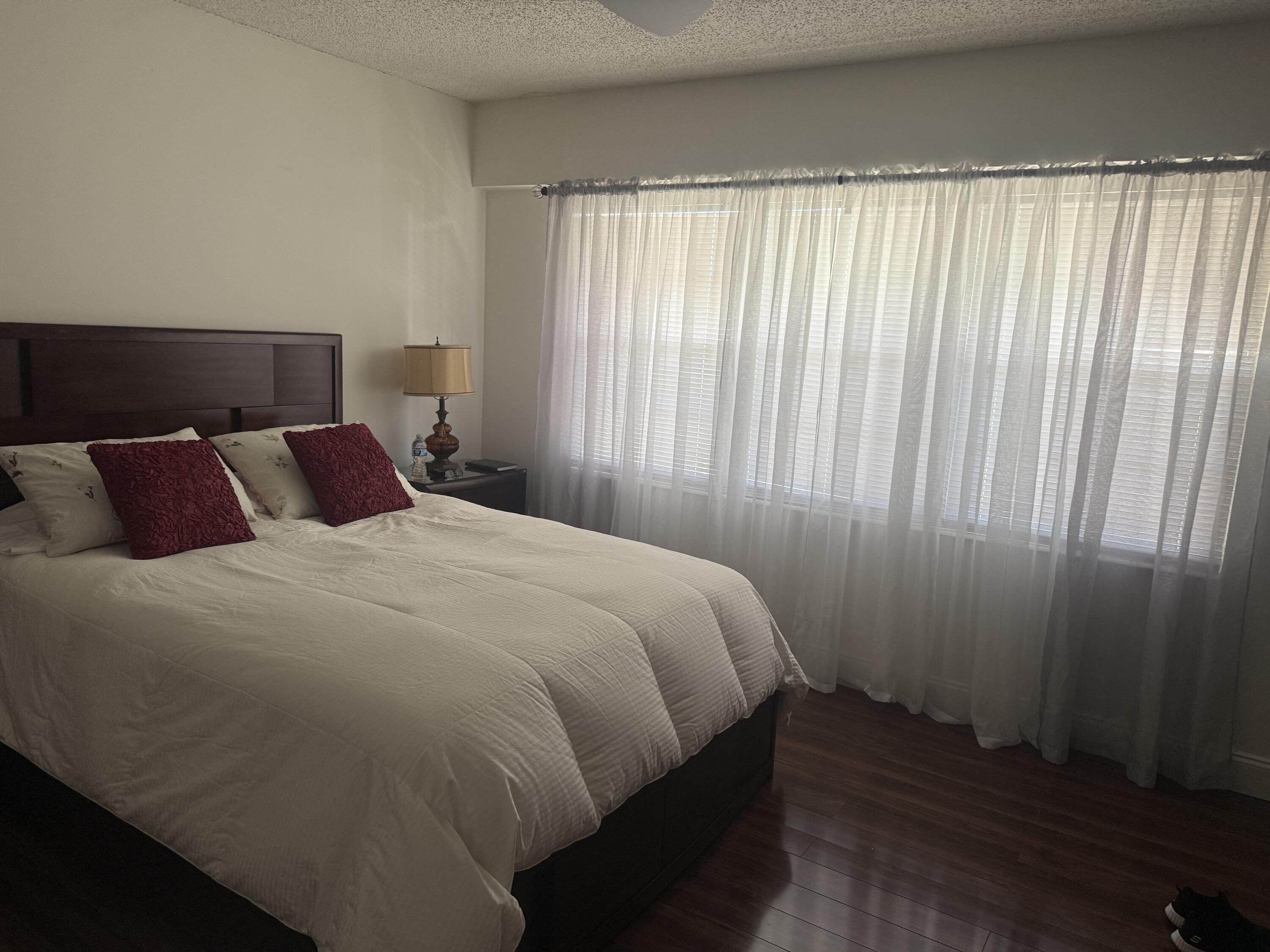 246 Preston F, Unit 246 Boca Raton, FL 33434 - Photo 4 of 10 a bedroom with a bed and wooden floor