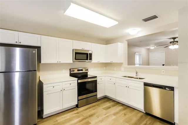 a kitchen with a sink stainless steel appliances and white cabinets