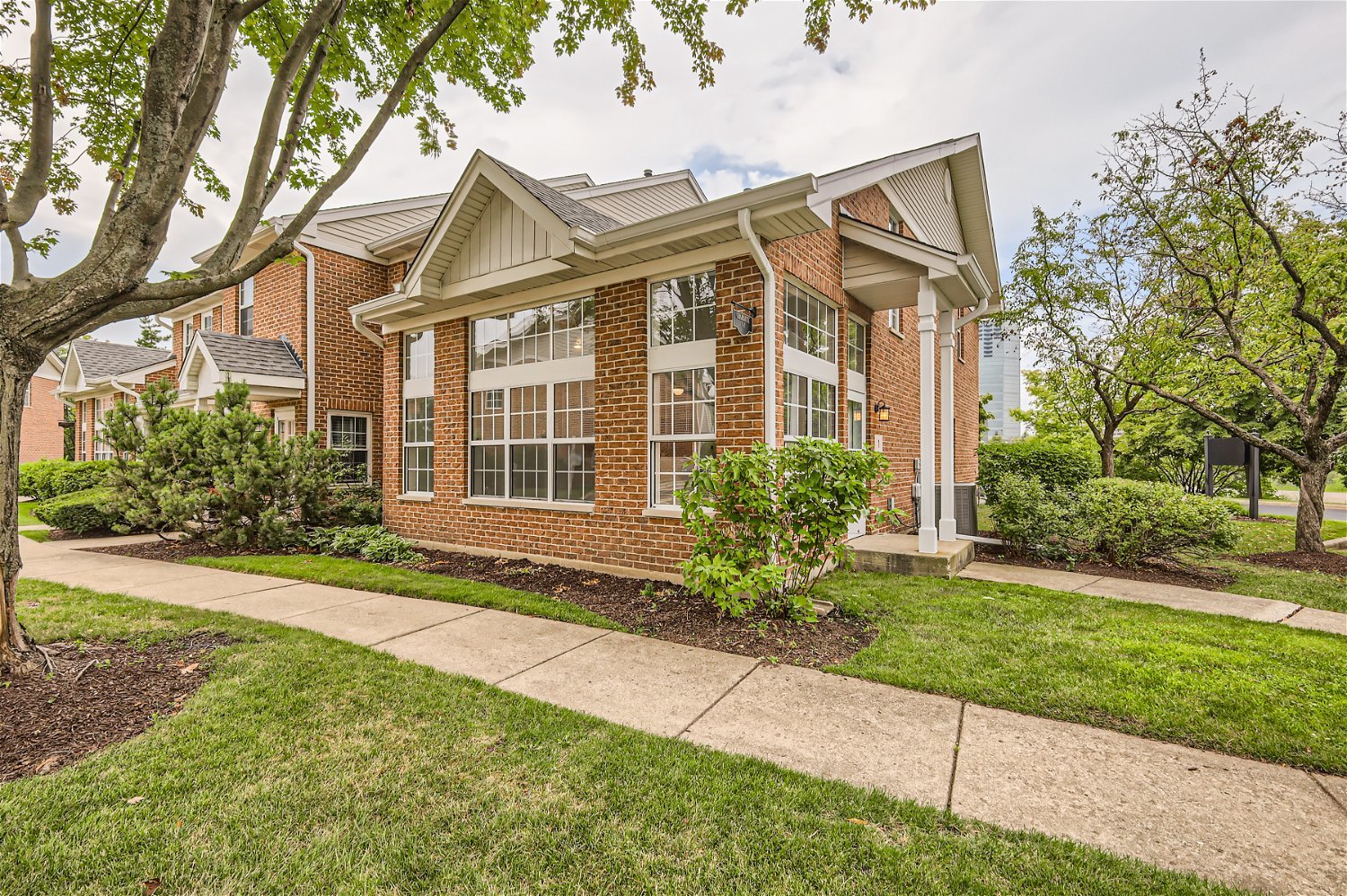 a view of a brick house with a yard and plants