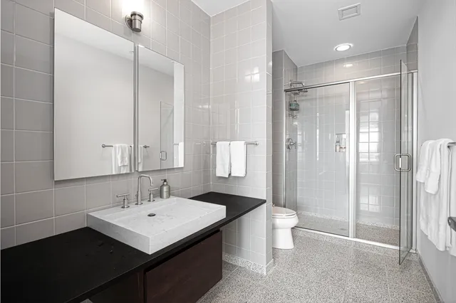 a bathroom with a sink a toilet a mirror and shower