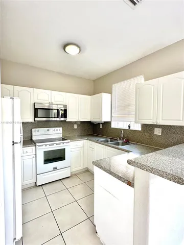 a kitchen with stainless steel appliances granite countertop a stove a sink and white cabinets