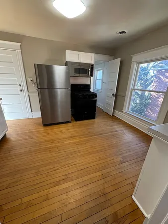 a kitchen with stainless steel appliances wooden floor and large window