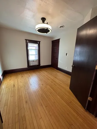 an empty room with wooden floor chandelier fan and windows