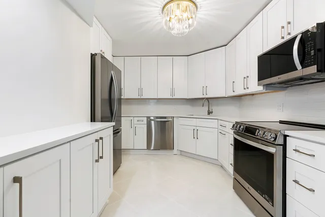 a kitchen with stainless steel appliances white cabinets and a stove top oven