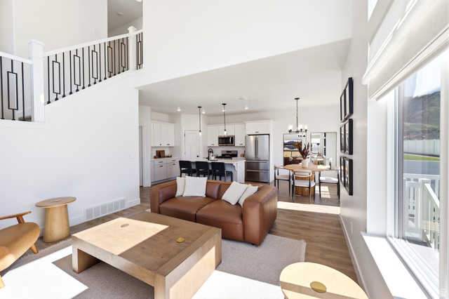 4646 Alder Drive, Unit 223 Mapleton, UT 84664 - Photo 7 of 35 Open concept living space featuring vaulted ceilings, wood-finish flooring, a contemporary staircase with black metal balusters, a kitchen with white cabinetry and stainless steel appliances, and a dining area with modern lighting