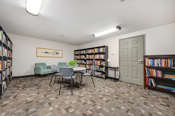 a living room with furniture a bookshelf and a window