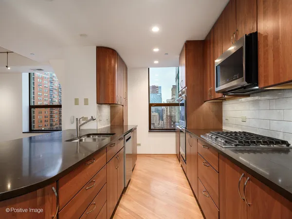 a kitchen with stainless steel appliances granite countertop a stove a sink and a microwave