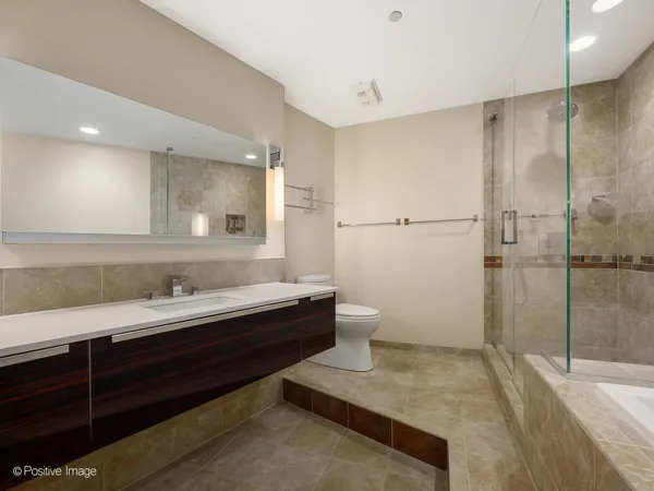 a bathroom with a double vanity sink toilet mirror and shower