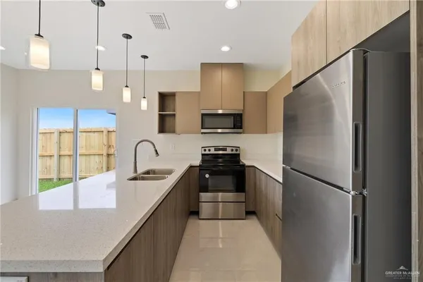 a kitchen with stainless steel appliances granite countertop a refrigerator a sink dishwasher a stove and a refrigerator with wooden floor