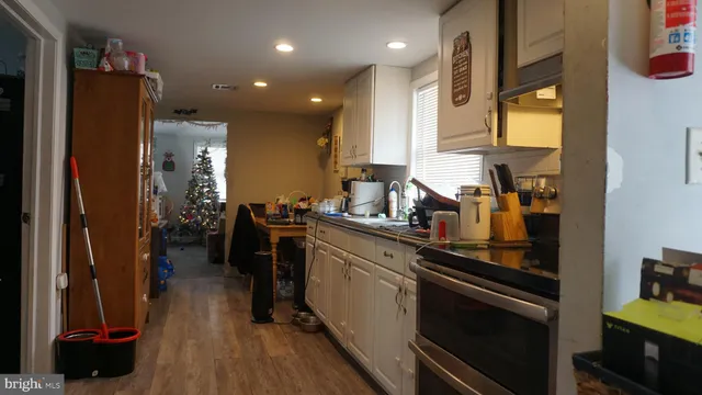 a kitchen with stainless steel appliances granite countertop a refrigerator a sink a stove and white cabinets