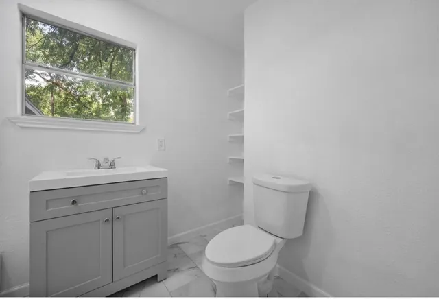 a bathroom with a toilet a sink a window and mirror