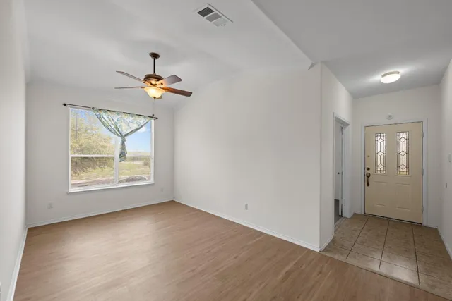 an empty room with a window and a ceiling fan