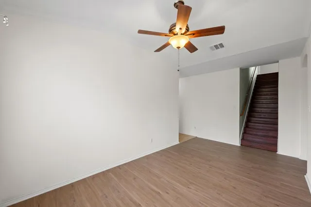an empty room with wooden floor fan and white walls