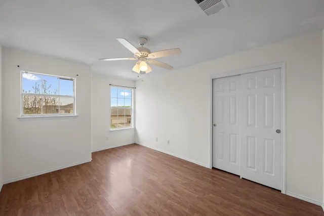 a view of an empty room with wooden floor and window