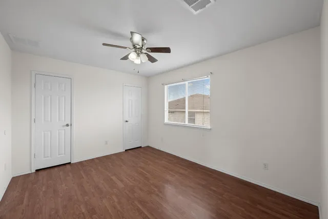 a view of empty room with wooden floor and fan