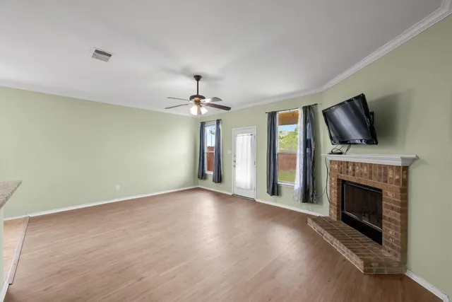 an empty room with windows fireplace and wooden floor