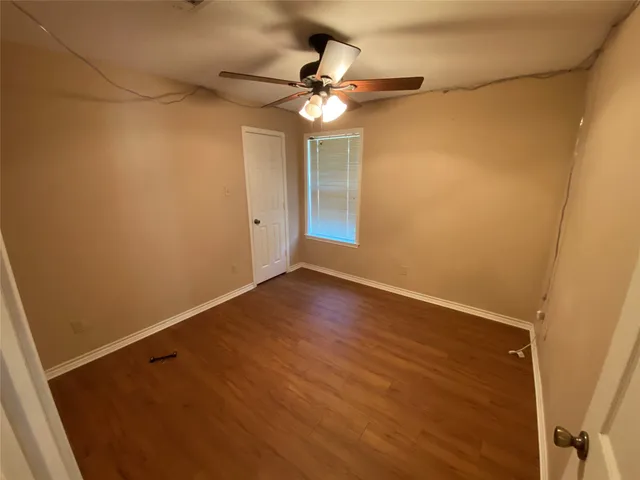 en empty room with wooden floor and fan