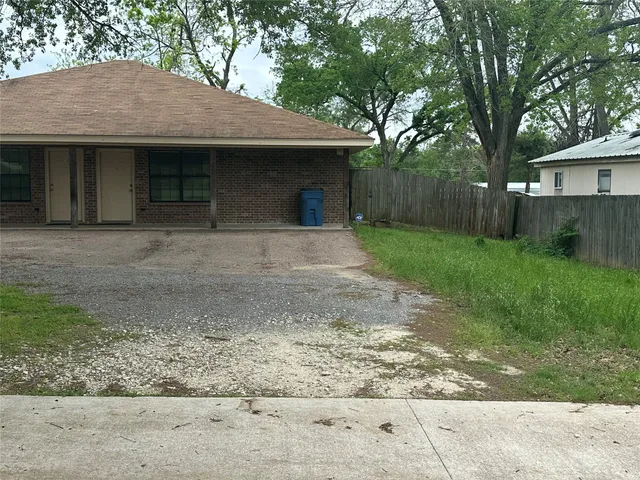 a front view of a house with a garden and trees