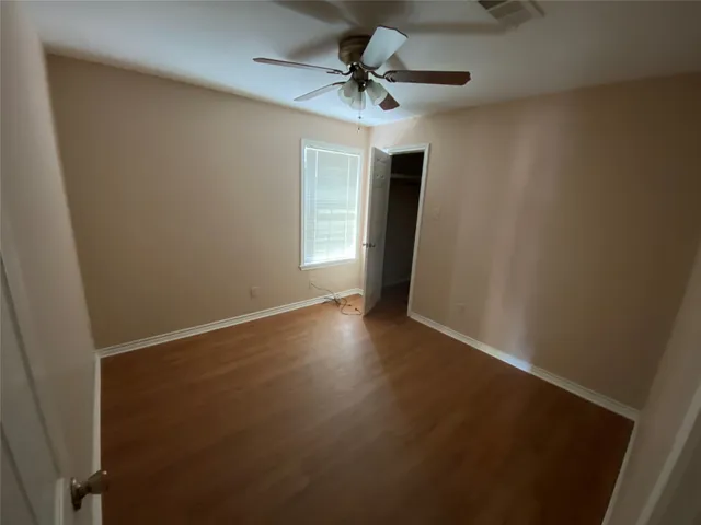 an empty room with a window and a fan