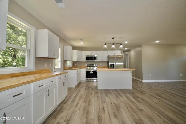 a large kitchen with stainless steel appliances kitchen island a large counter top and a wooden floors