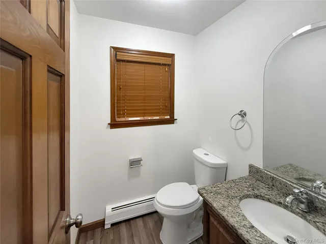 a bathroom with a granite countertop toilet sink and mirror