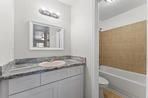 a bathroom with a granite countertop sink a toilet and bathtub