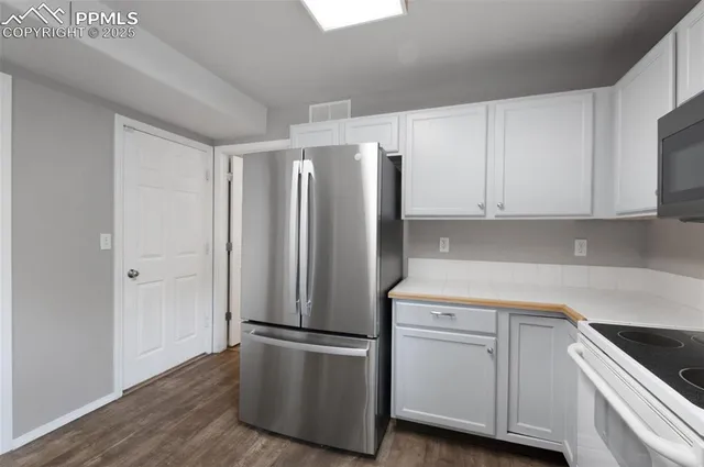 a kitchen with stainless steel appliances white cabinets and a refrigerator