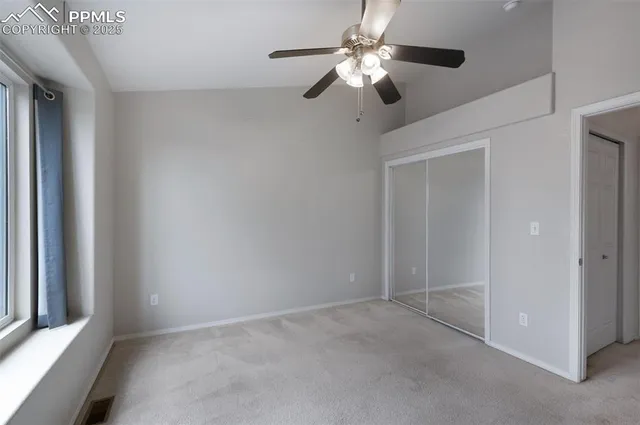 an empty room with a chandelier fan and windows