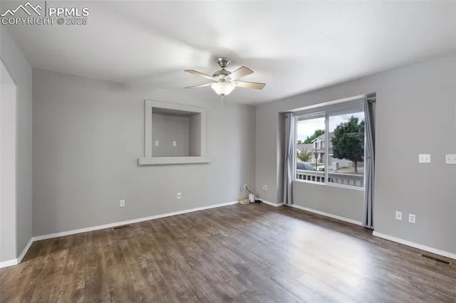 a view of an empty room with a window and a kitchen