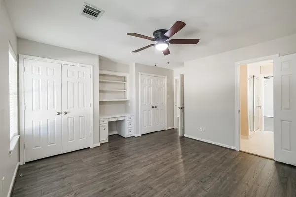 an empty room with wooden floor fan and windows