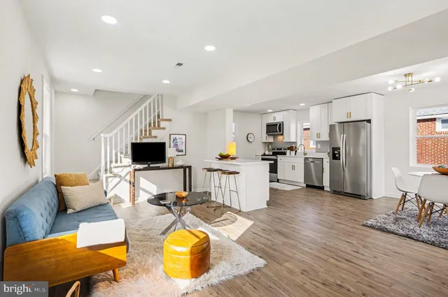 a living room with furniture kitchen view and a wooden floor