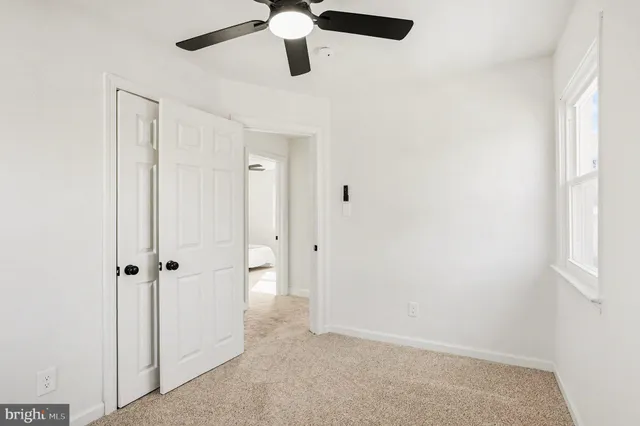 a view of a hallway with a chandelier fan and closet