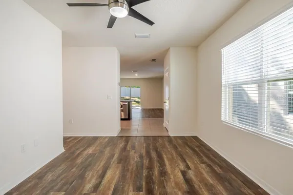 a view of empty room with wooden floor and fan