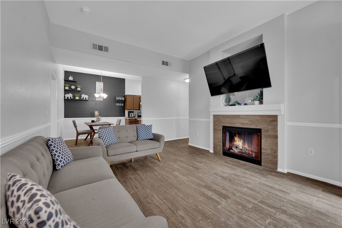 2305 West Horizon Ridge Parkway, Unit 3512 Henderson, NV 89052 - Photo 5 of 29 Living room featuring a tiled fireplace, a chandelier, and wood finished floors