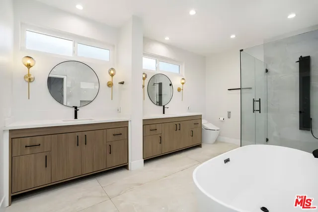 a spacious bathroom with a double vanity sink mirror and bathtub