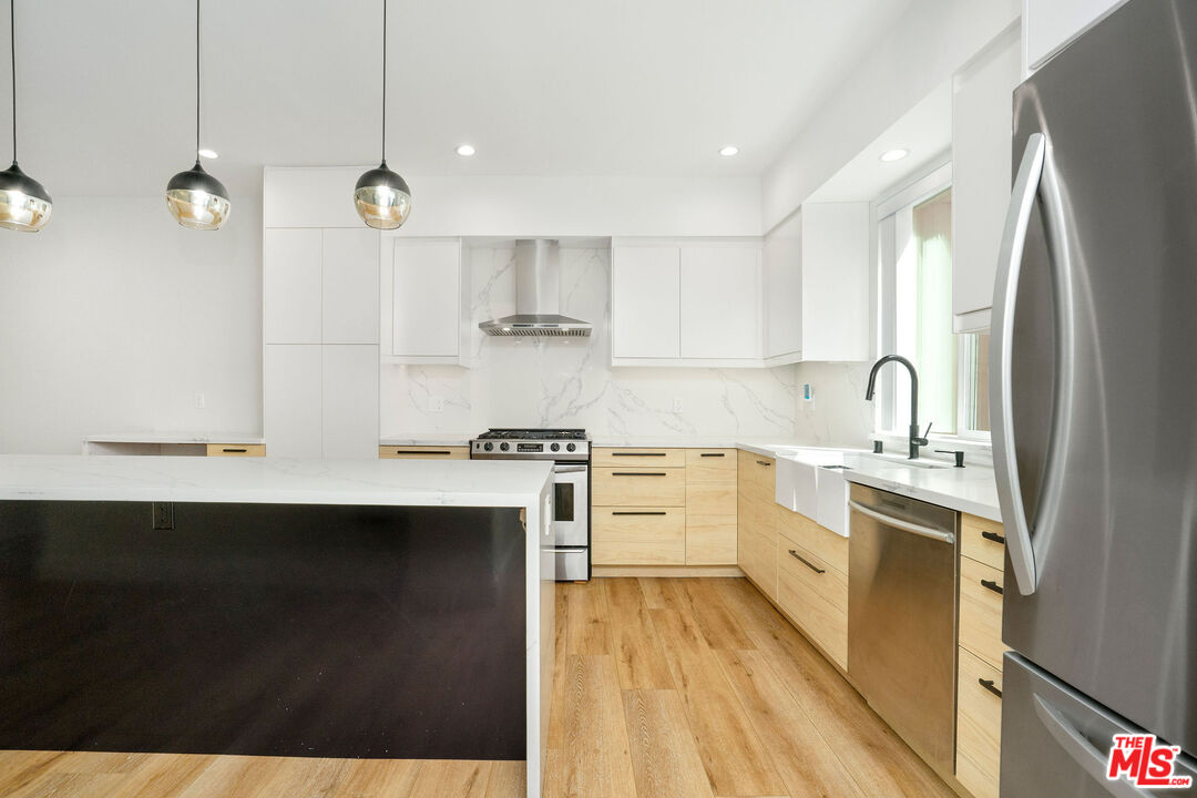 5923 Etiwanda Avenue, Unit 106 Tarzana, CA 91356 - Photo 2 of 27 a kitchen with kitchen island a sink stainless steel appliances and cabinets