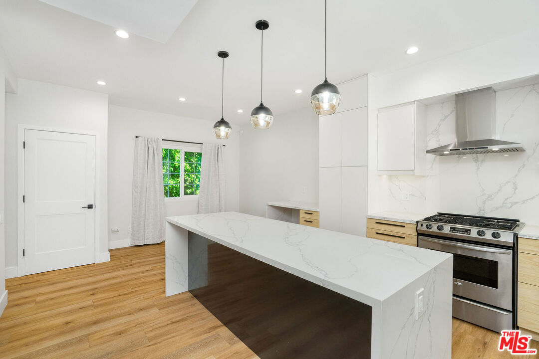 5923 Etiwanda Avenue, Unit 106 Tarzana, CA 91356 - Photo 8 of 27 a kitchen that has a sink a stove and a wooden floor