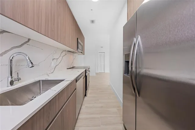 a kitchen with kitchen island granite countertop a sink and refrigerator