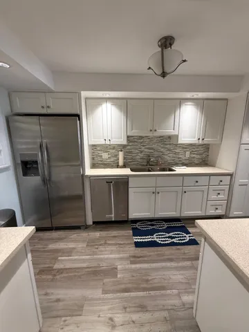 a kitchen with granite countertop a sink cabinets and stainless steel appliances